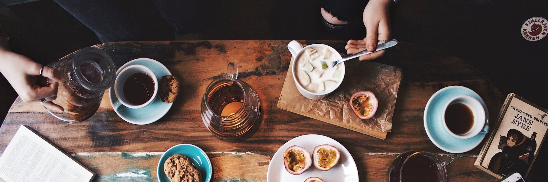 person sitting near table with teacups and plates